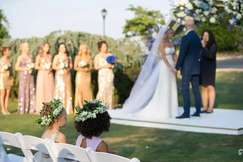 The vows beneath the arch, the bridesmaids behind and flower girls watching from the front row.