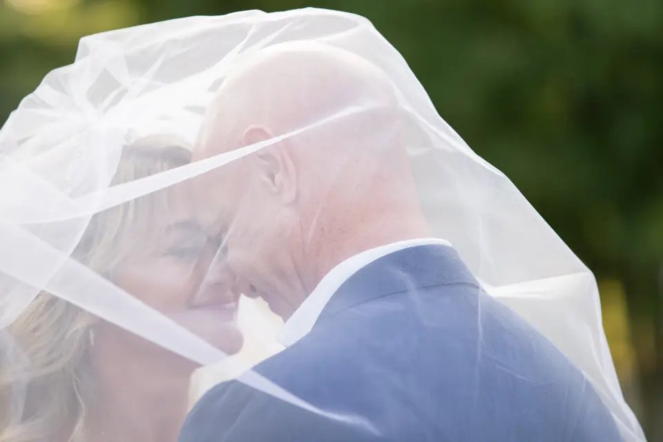 The bride and groom touch foreheads beneath her veil.