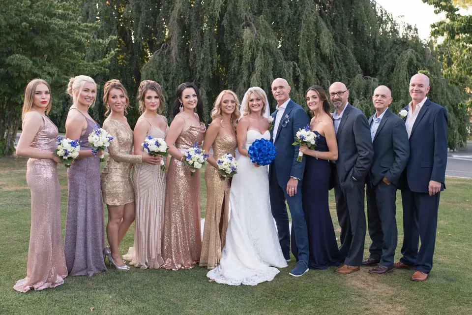 The wedding party on the lawn, the bridesmaids in gold and blush and the groomsmen in navy.