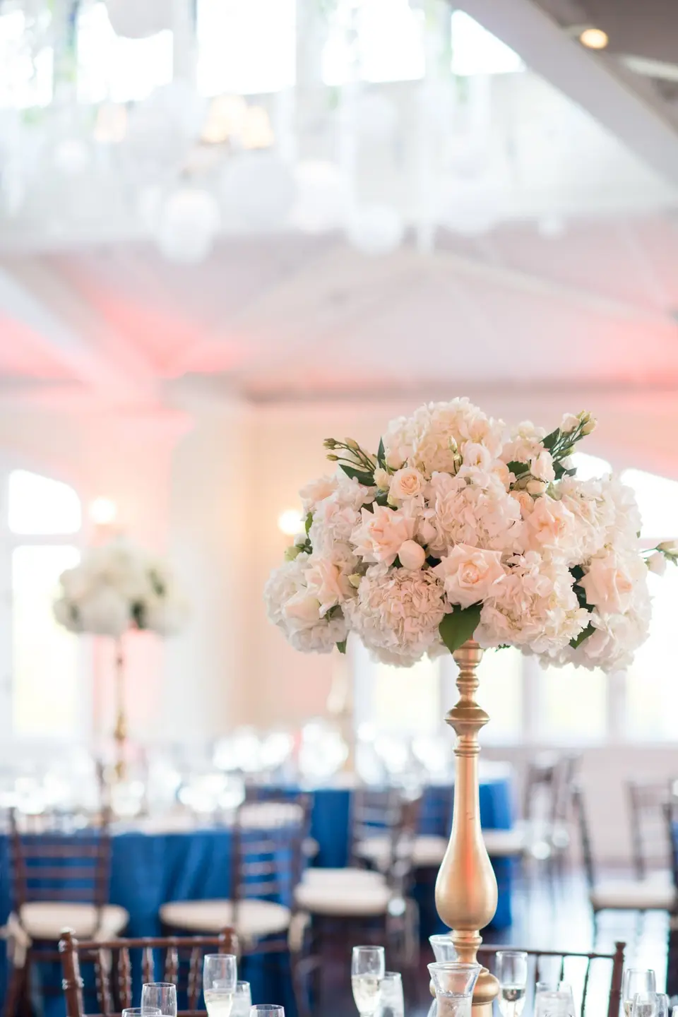 Close on a tall arrangement of blush and white flowers above the tables.