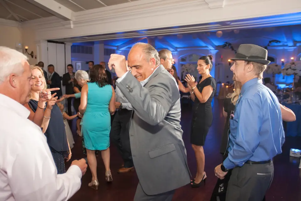 Guests dance beneath blue uplighting in the reception room.