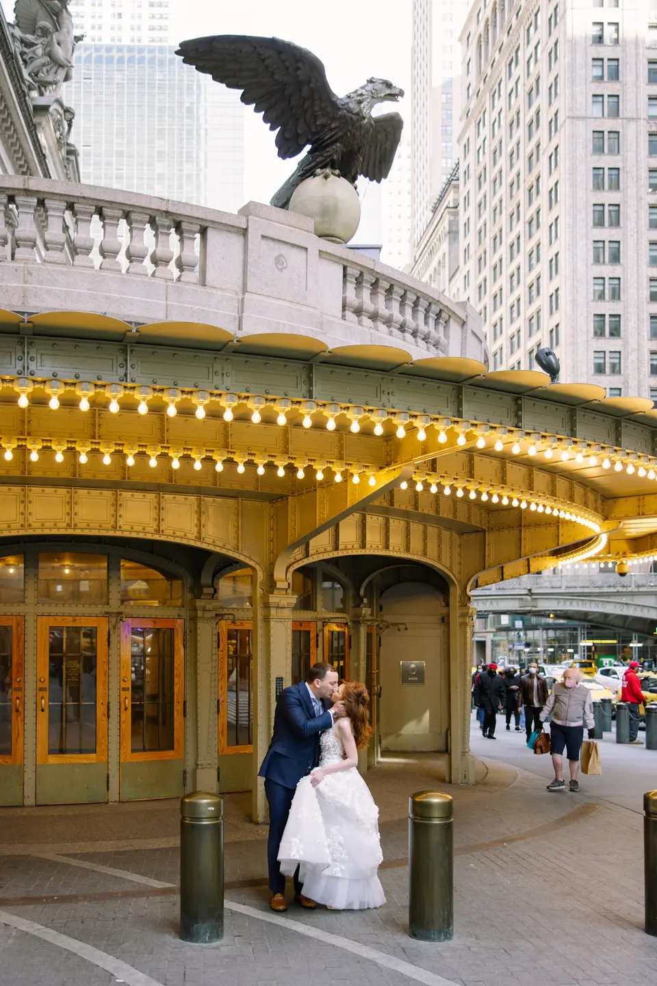 The couple kiss beneath the lit canopy at Grand Central's entrance, the bronze eagle above.