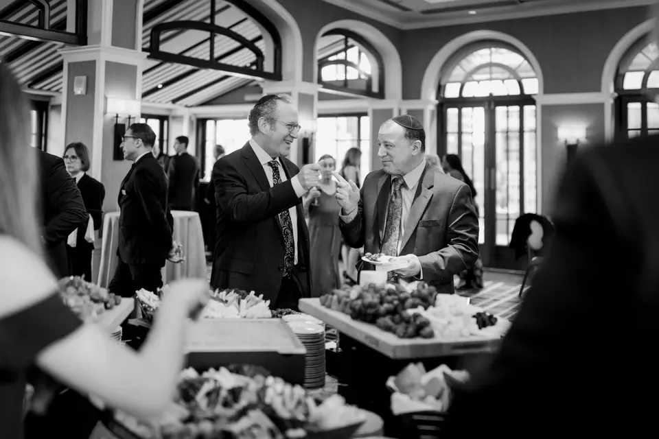 Guests talk over the cocktail hour spread. Black and white.